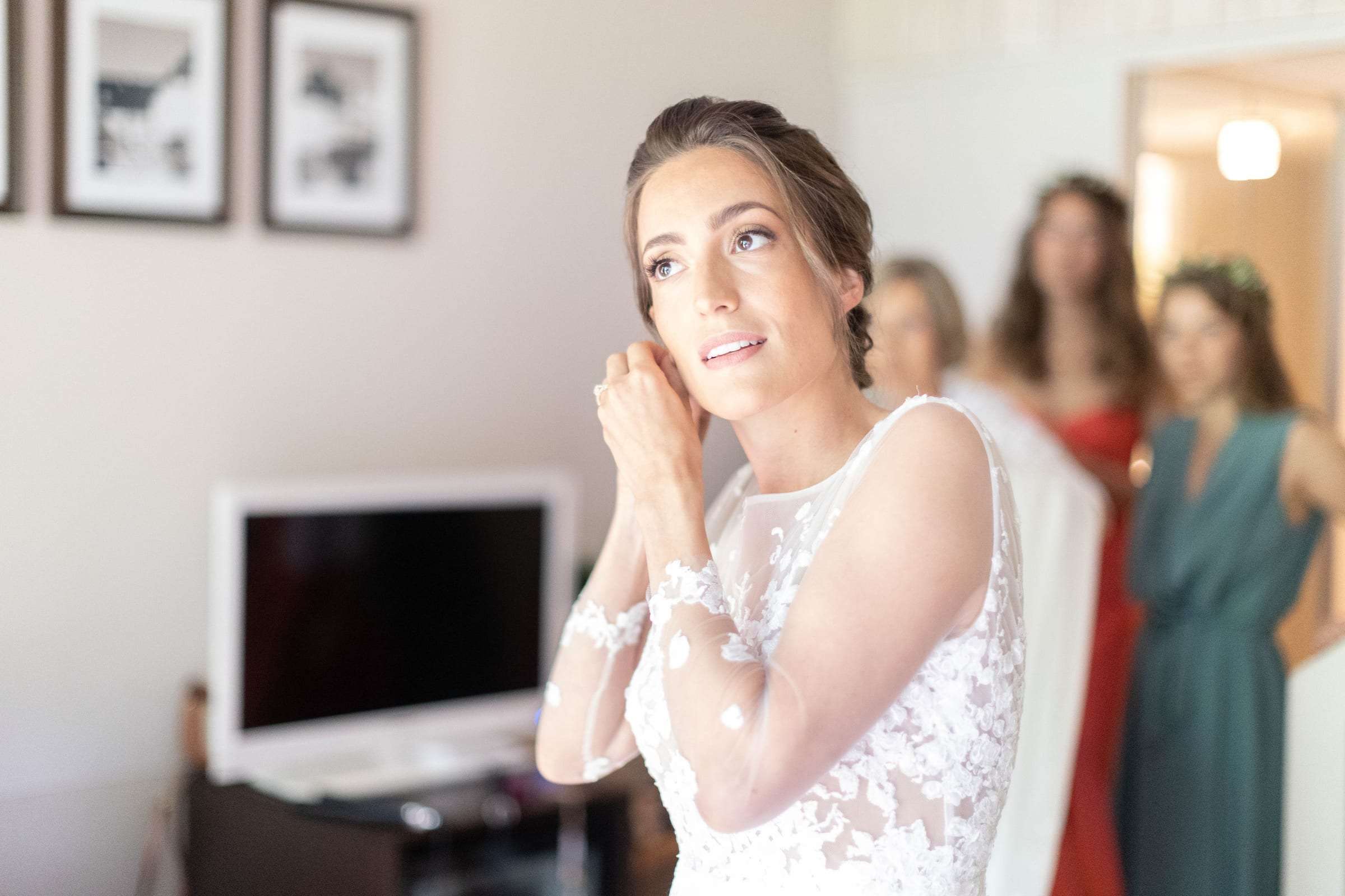La mariée ajuste ses boucles d'oreilles, entourée de ses amies