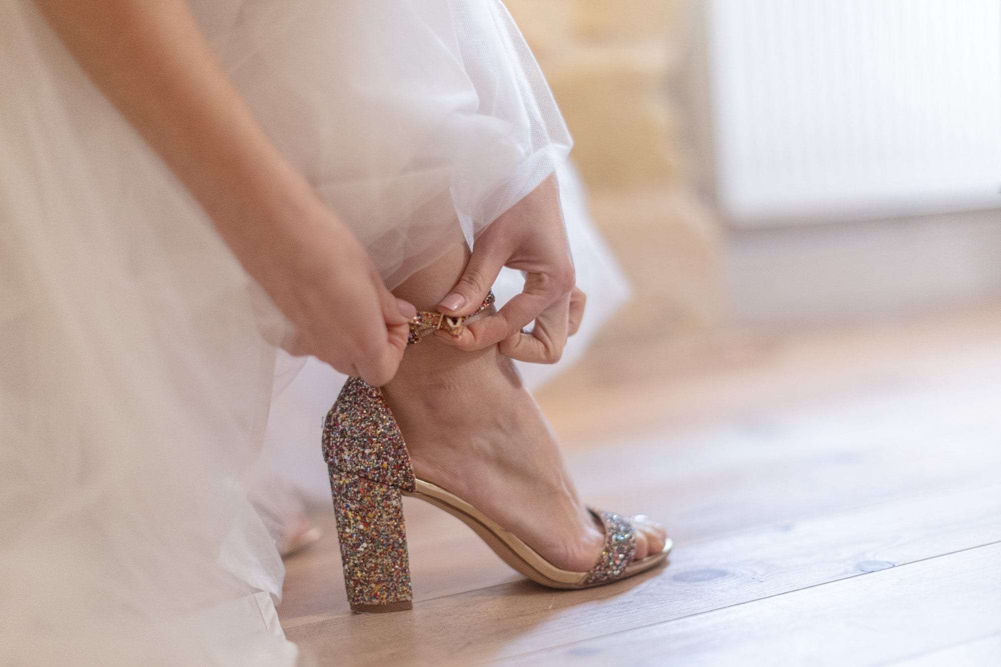 La mariée attache sa sandale pailletée