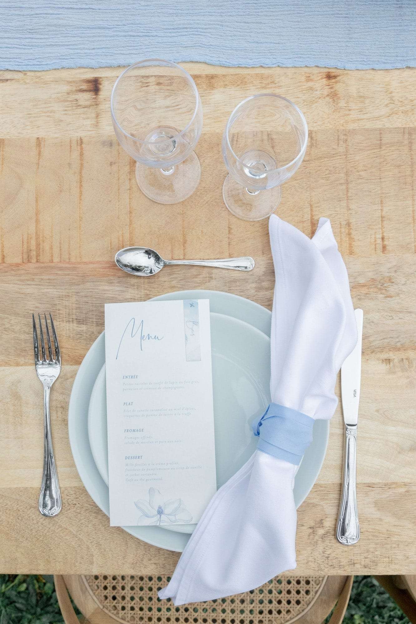 Table de mariage, assiette céramique et serviette nouée d'un ruban bleu