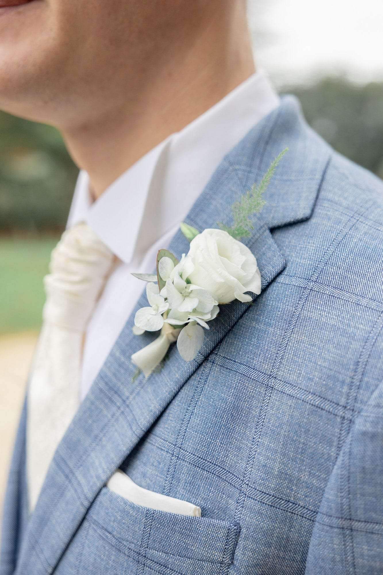 Boutonnière de fleurs blanches sur un costume bleu clair