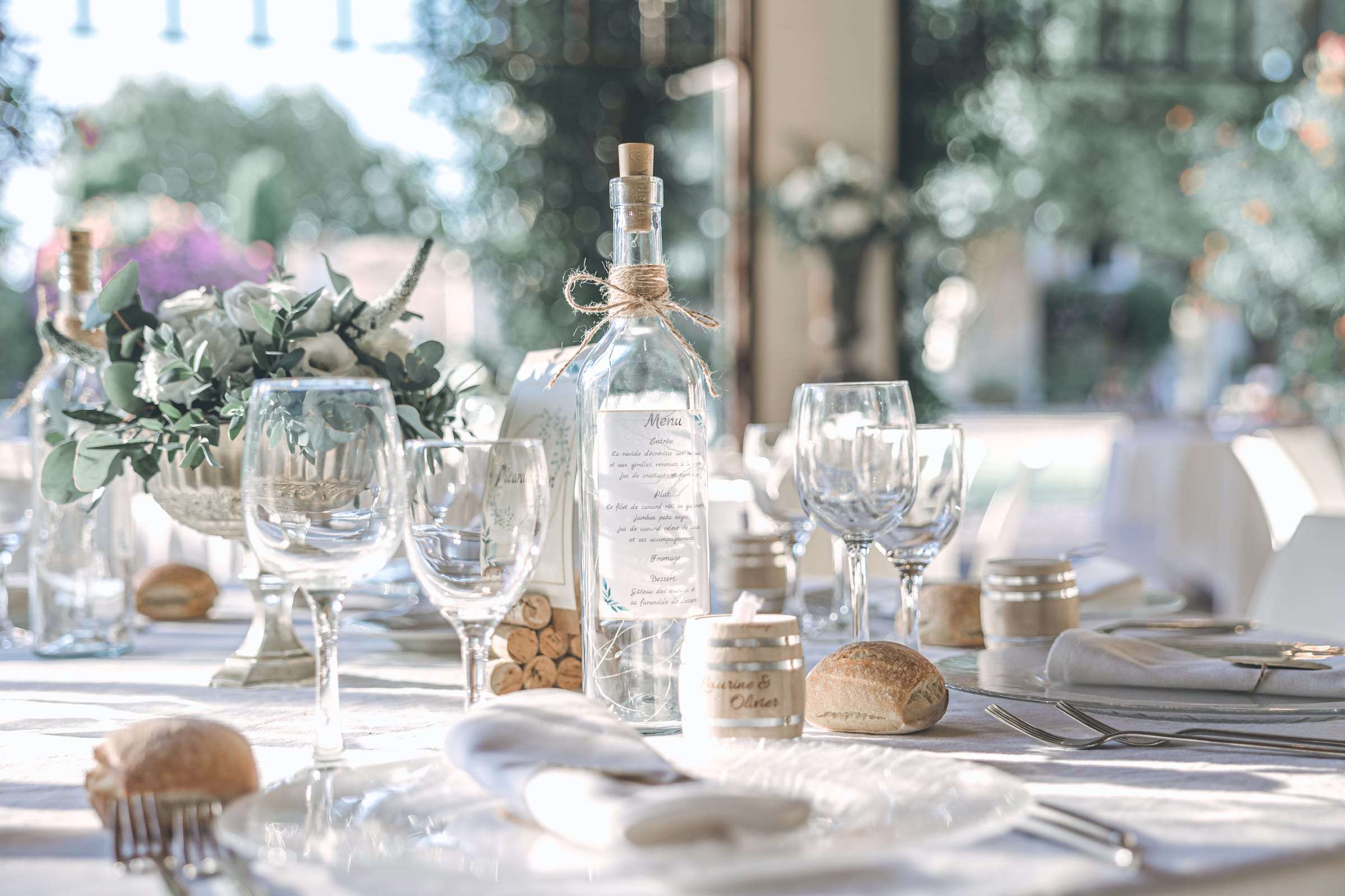 Table de réception dressée, verres, carafe et fleurs blanches