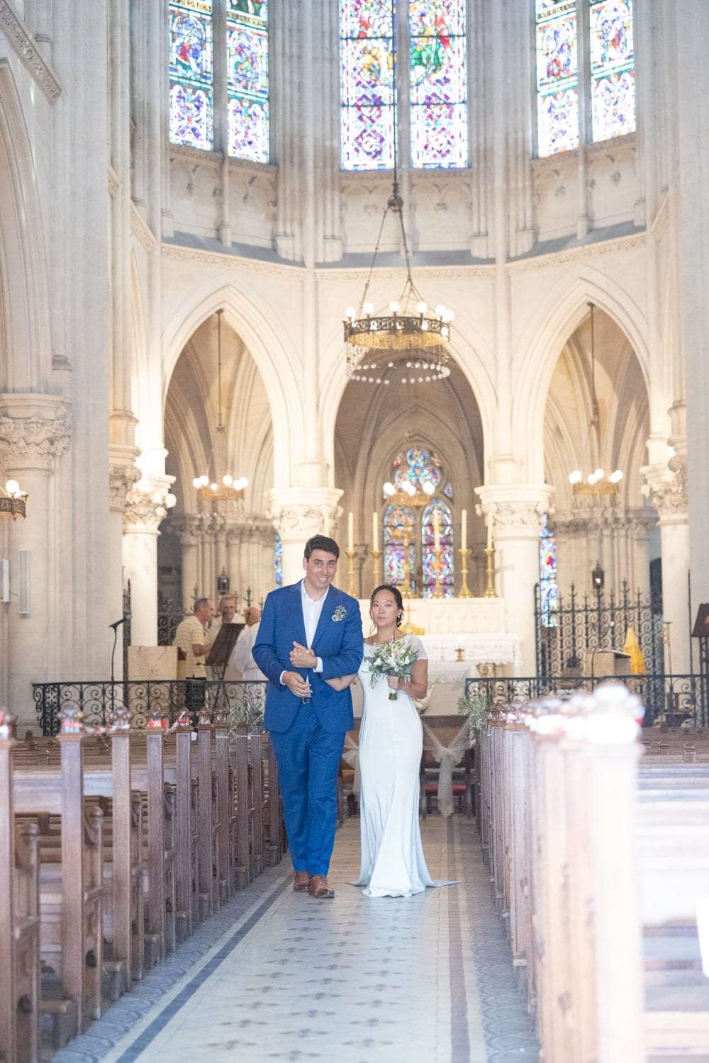 Les mariés devant l'autel d'une église aux vitraux lumineux