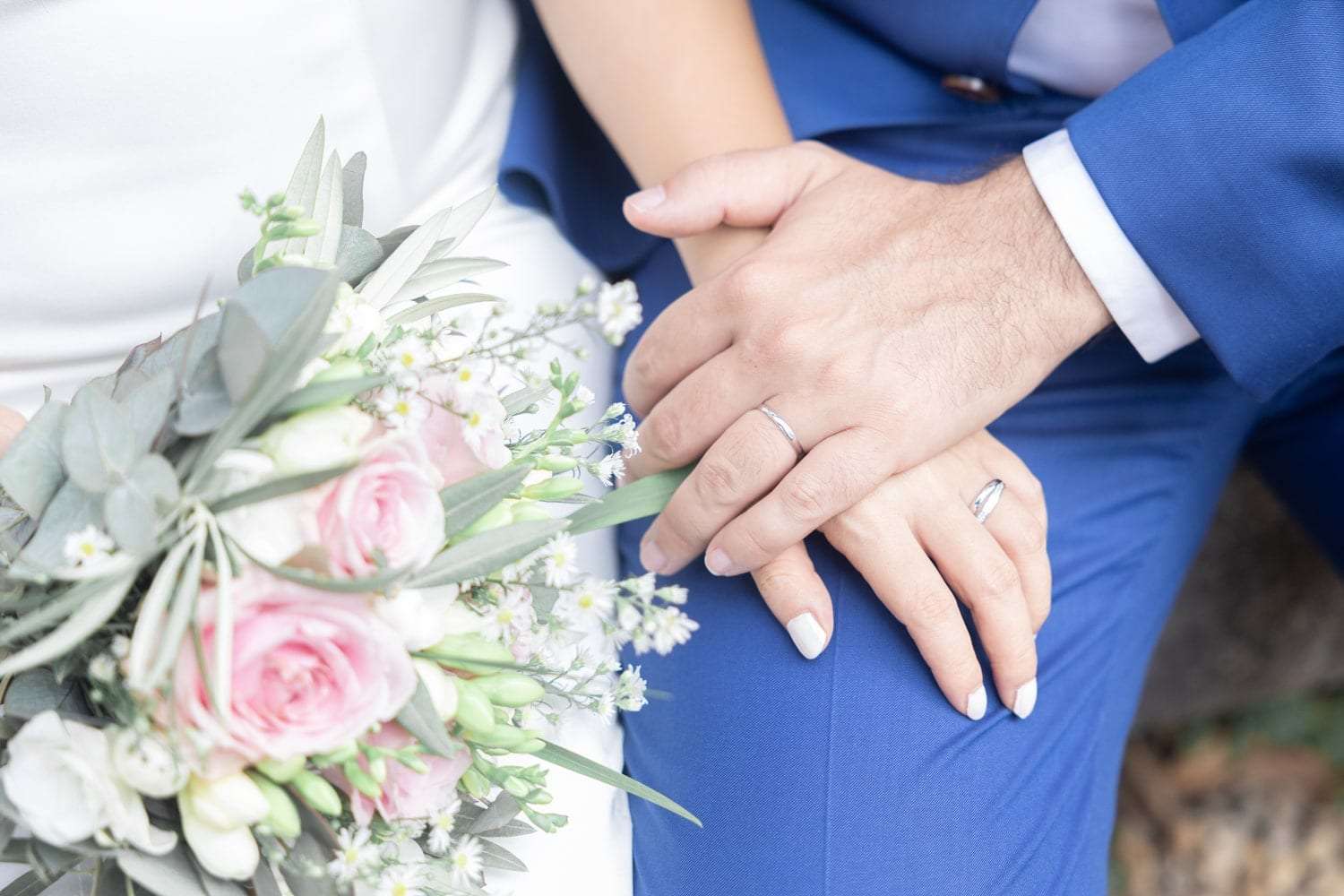La main de la mariée posée sur la veste du marié, bouquet d'eucalyptus