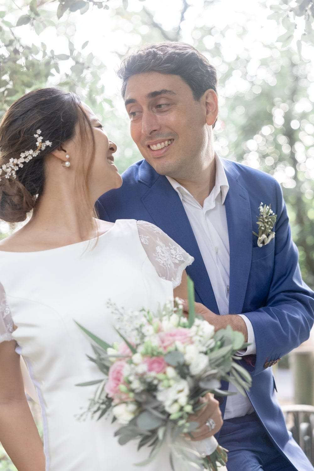 Les mariés rient ensemble, la mariée tient un bouquet pastel