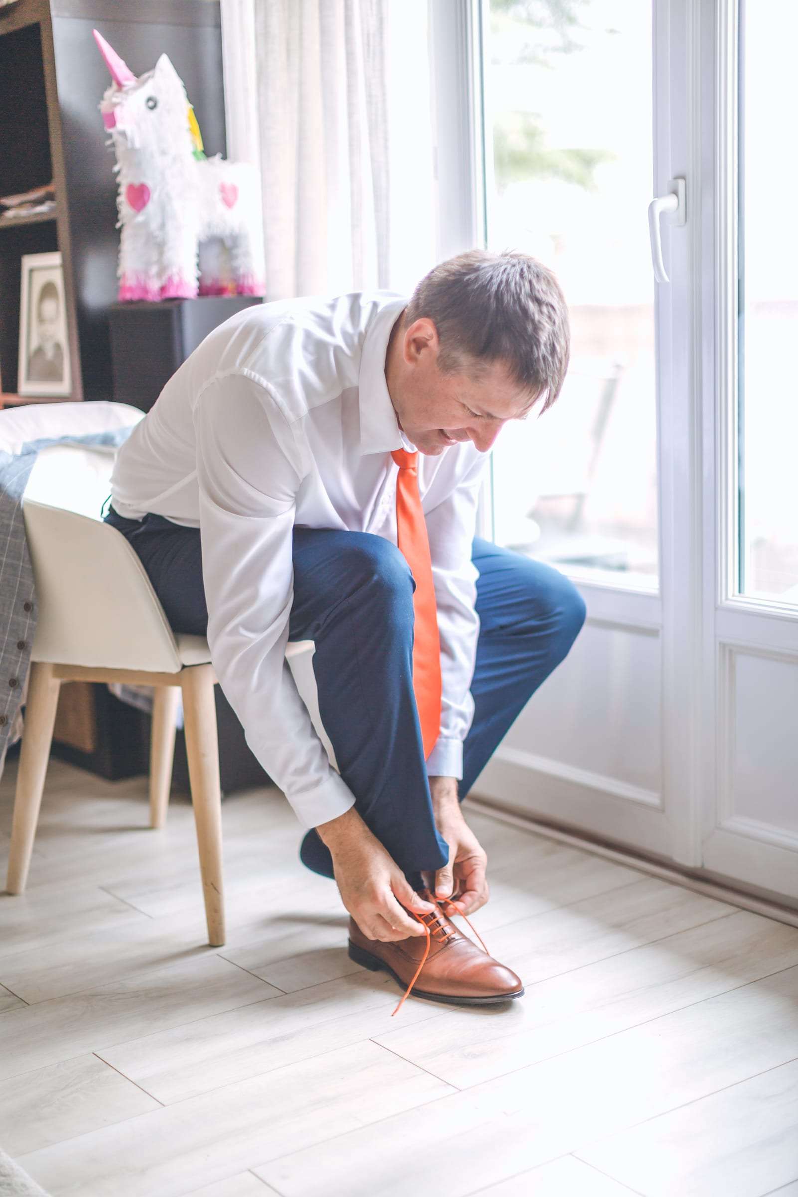 Le marié lace ses chaussures près de la fenêtre