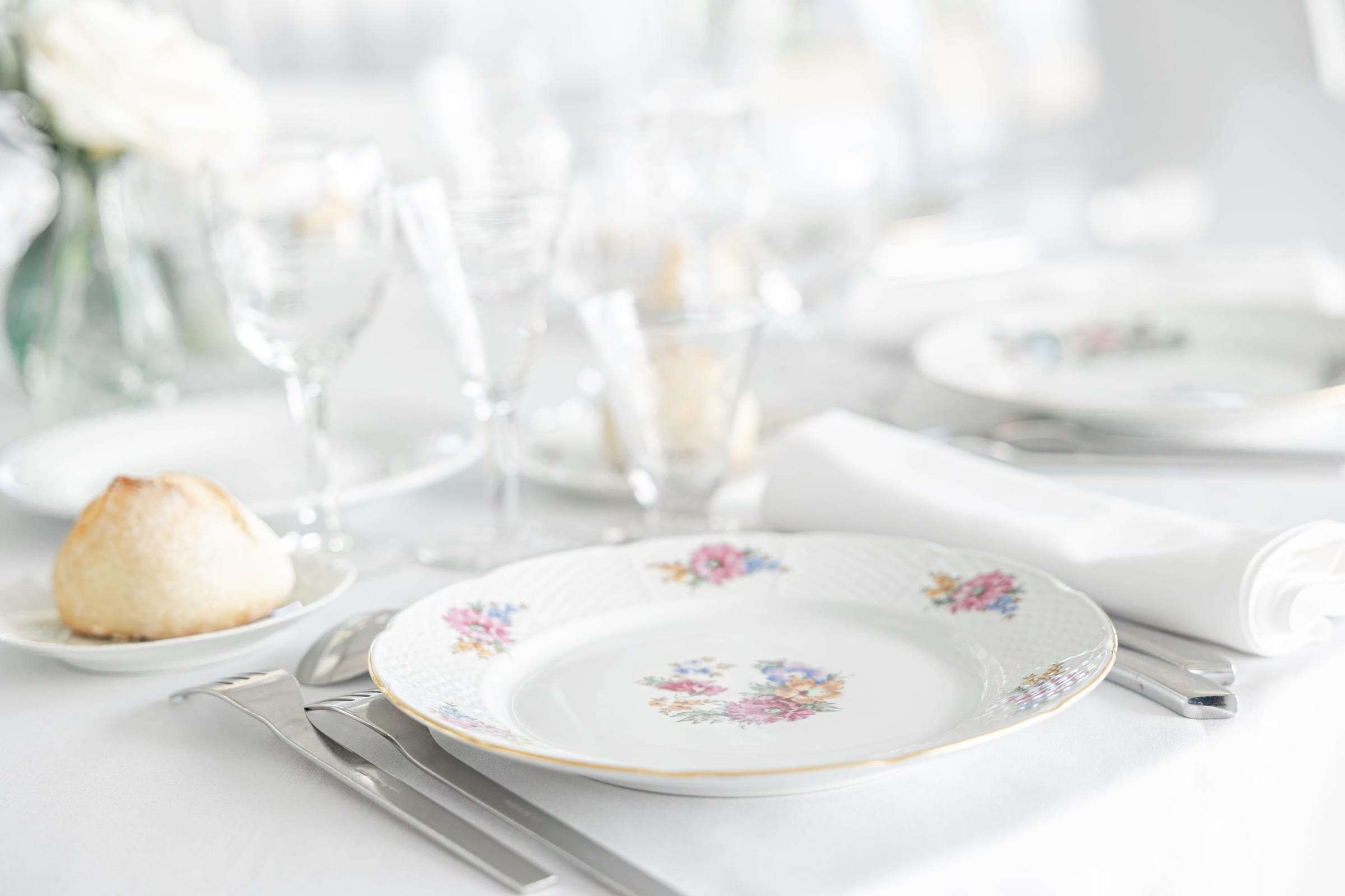 Table dressée de vaisselle blanche fleurie pour le dîner