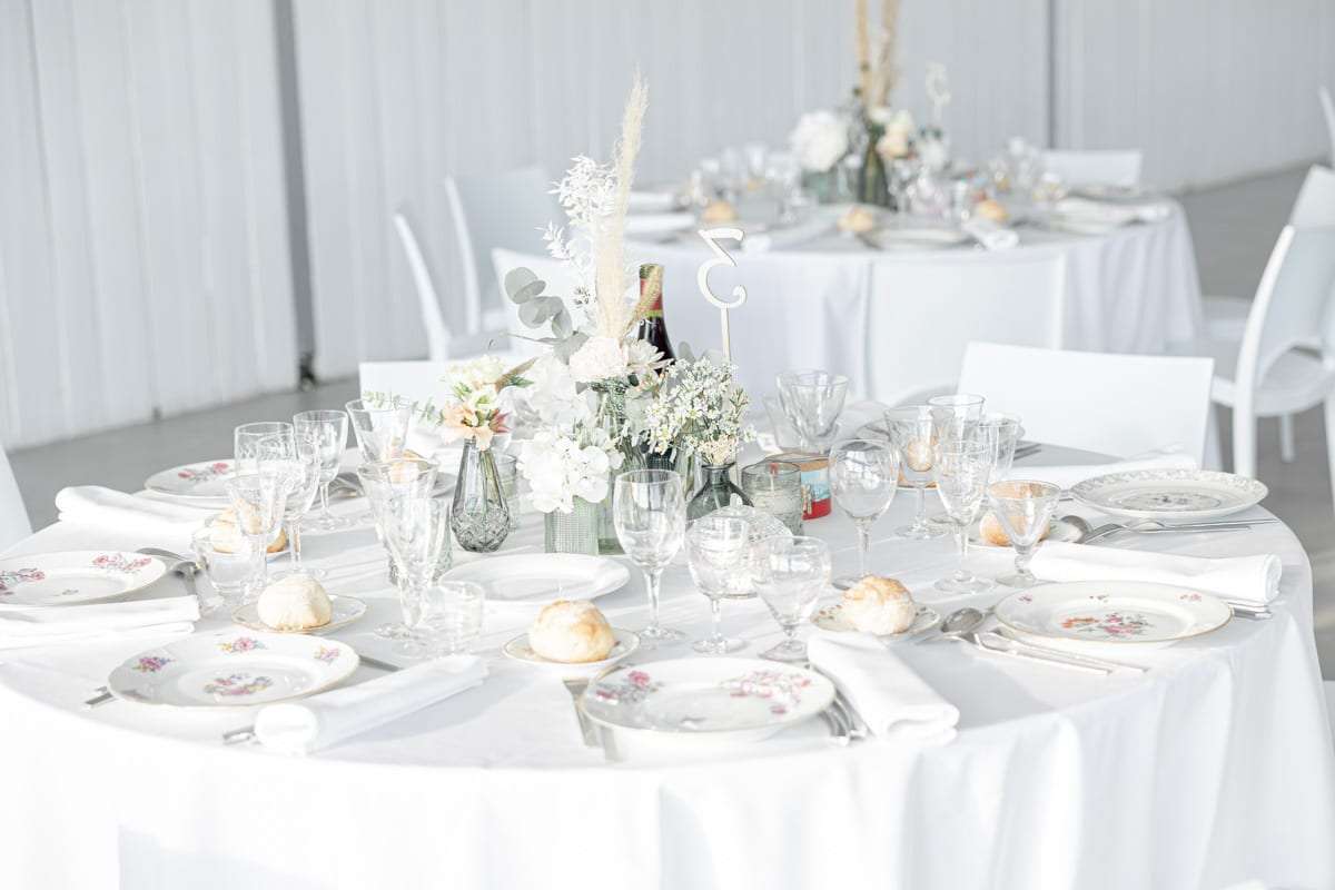 Salle de réception blanche, tables rondes fleuries