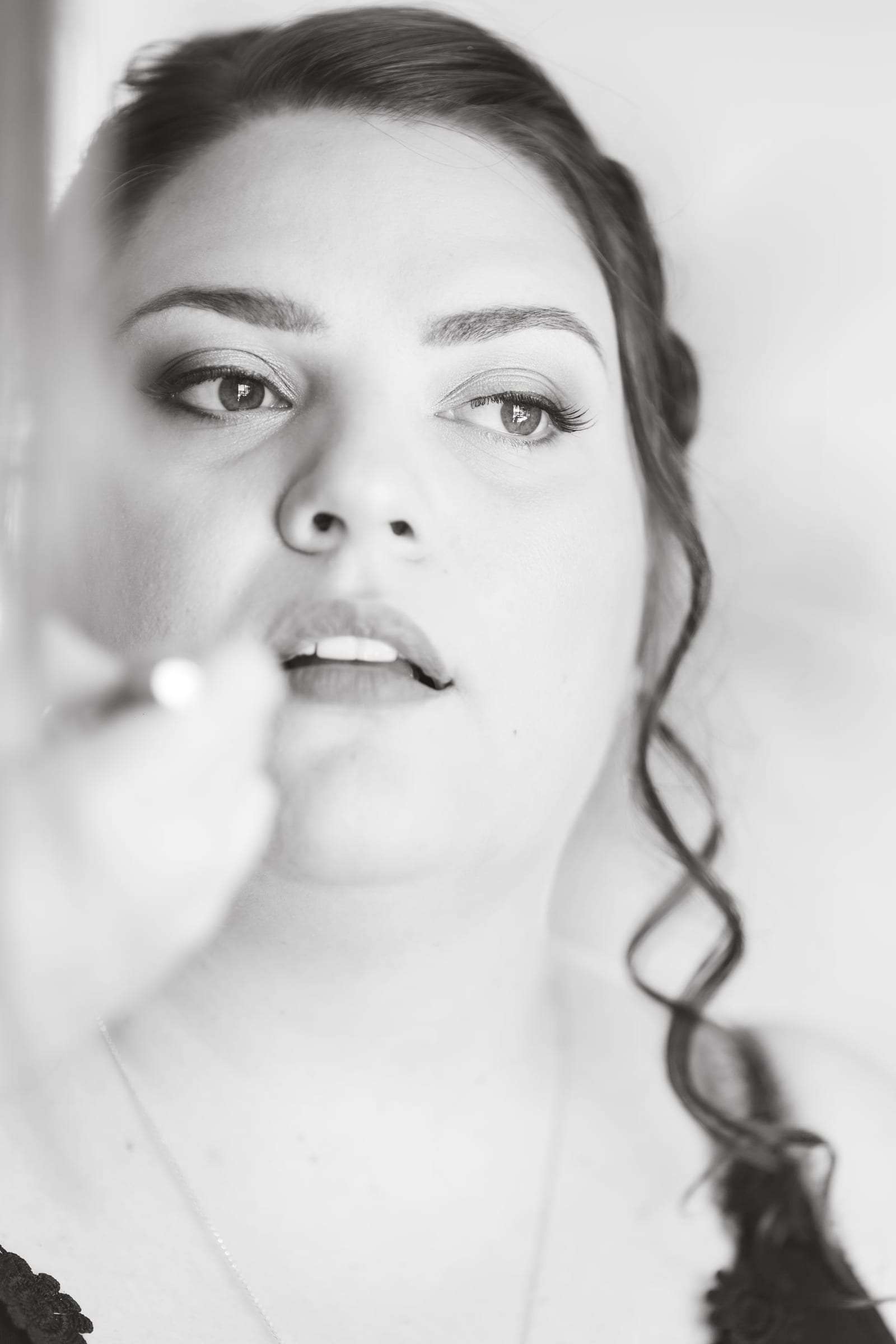 Portrait noir et blanc de la mariée pendant le maquillage